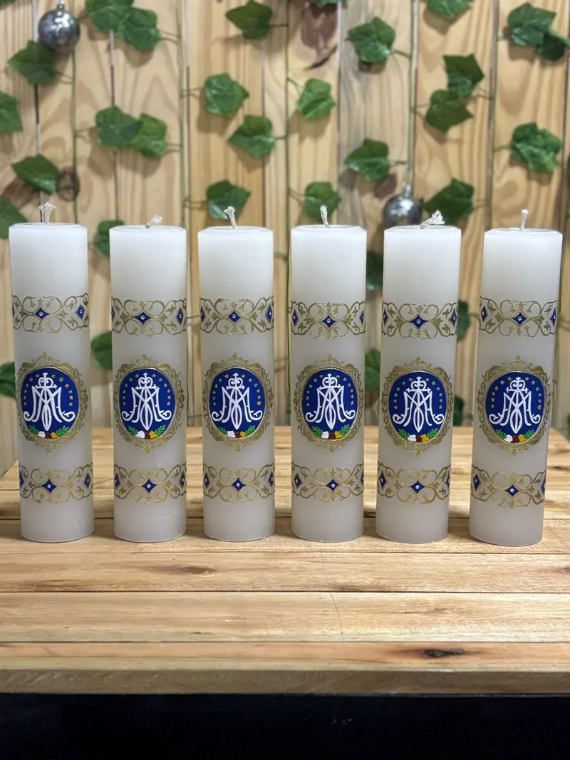 Velas brancas com o monograma de Maria em azul e detalhes dourados