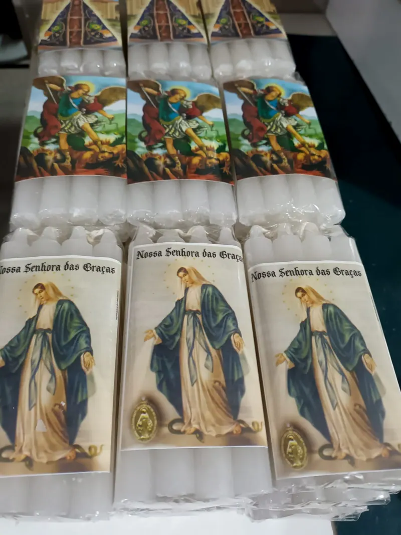 Velas palito em pacote, com estampas de Nossa Senhora das Graças e São Miguel